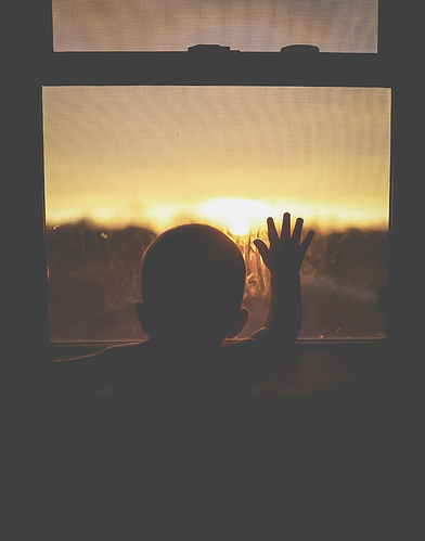 Child looking out the window at sunset. 